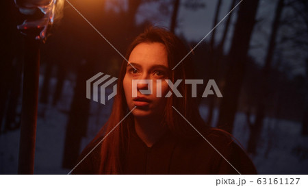 Young confused woman traveler walking in the woods at night holding a torch 63161127