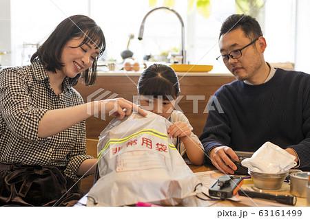 非常持ち出し袋に荷物を入れる子どもを見守る夫婦 63161499