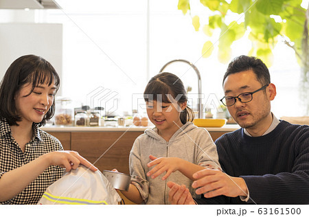 非常持ち出し袋に荷物を入れる子どもを見守る夫婦 63161500