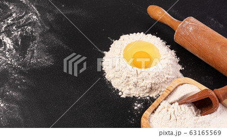Rolling pin and white flour on a dark background 63165569