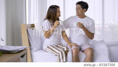 Happy asian couple drinking coffee together in a bedroom. 63167300