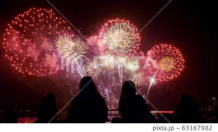 People watching beautiful fireworks together by the sea at night. People watching beautiful fireworks together by the sea at night. 63167982