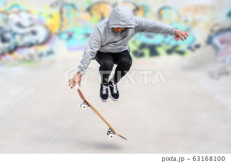 young skater doing jump trick at skate park. 63168100