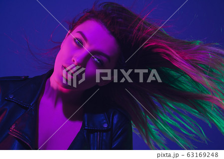 Caucasian woman's portrait isolated on blue studio background in neon light 63169248