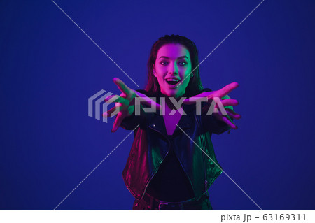Caucasian woman's portrait isolated on blue studio background in neon light Caucasian woman's portrait isolated on blue studio background in neon light 63169311