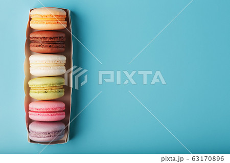 Multicolored French macaroni macaroni cookies in a white box on a blue background. 63170896