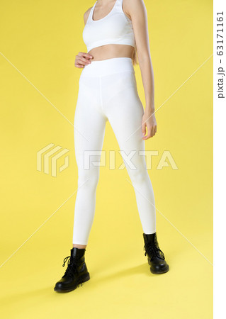 Young woman in white blank leggings and a crop top on a yellow background. Mock-up. 63171161