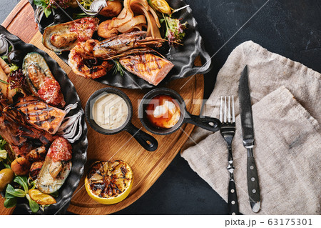grilled seafood platter. Assorted delicious grilled seafood with vegetables. Grilled mixed bastards with pepper sauce and vegetables. Blue background grilled seafood platter. Assorted delicious grilled seafood with vegetables. Grilled mixed bastards with pepper sauce and vegetables. Blue background 63175301