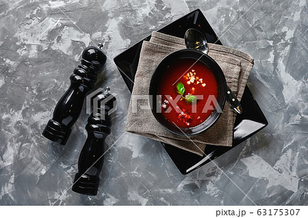 Tomato soup in a black bowl on a gray stone background. View from above. Copy space. Gray background. calm light. Food concept Tomato soup in a black bowl on a gray stone background. View from above. Copy space. Gray background. calm light. Food concept 63175307