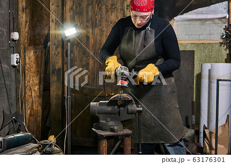 female artisan processes a metal artwork with an 63176301