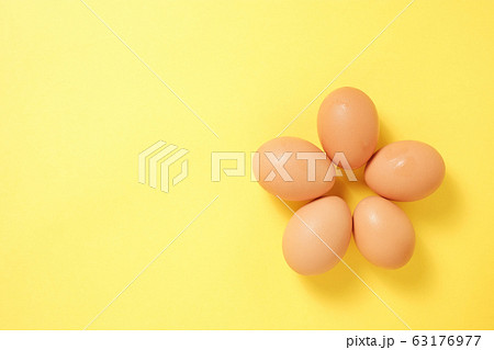 黄色い背景に五個花形に並んだ卵の写真素材