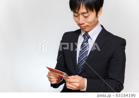 通帳を笑顔で見るスーツ姿の男性 63184190