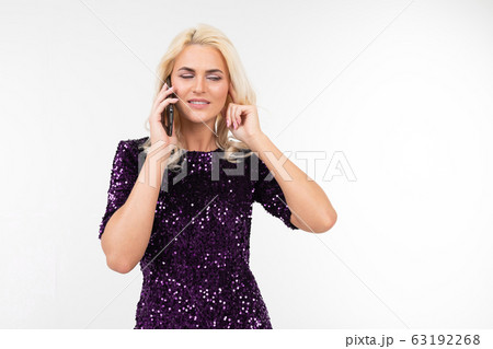 dazzling blonde business woman in purple shiny dress discussing business on the phone on a white 63192268