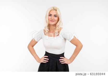 pretty blonde woman in white t-shirt posing with hands on hips on a white background 63193044