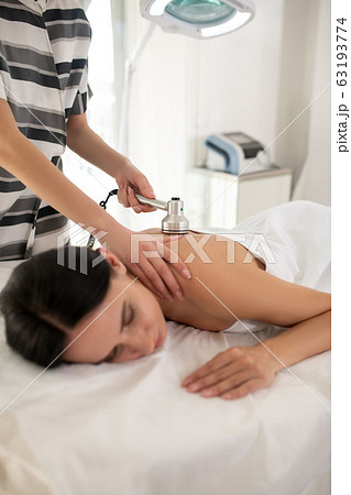 Cosmetologist in striped dress doing beauty procedures to the client Cosmetologist in striped dress doing beauty procedures to the client 63193774