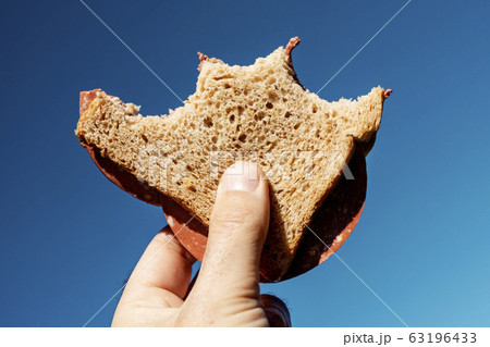 bitten vegan salami sandwich in the hand. bitten vegan salami sandwich in the hand. 63196433