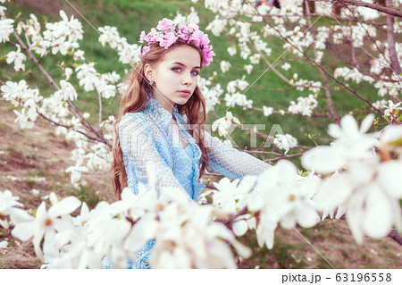 Attractive young girl among blooming magnolia Attractive young girl among blooming magnolia 63196558
