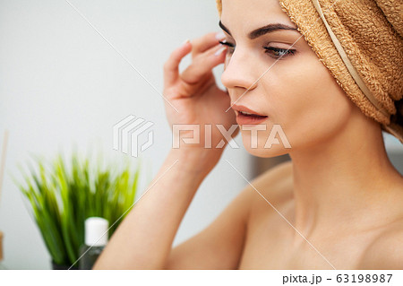 Cute girl puts patches under the eyes in the bathroom Cute girl puts patches under the eyes in the bathroom 63198987
