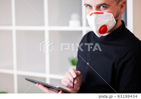 Man working in the office wearing a mask for protection from coronavirus 63199434