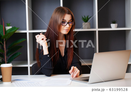 Young pretty woman working at the computer in the office and filling documents 63199528