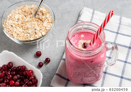 Freshly homemade smoothie with cranberries, oatmeal and yogurt in a mug jar on a gray table. Healthy eating concept Freshly homemade smoothie with cranberries, oatmeal and yogurt in a mug jar on a gray table. Healthy eating concept 63200459