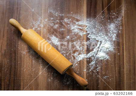 Flour is scattered on a brown wooden background-table and a rolling pin lies. View from above Flour is scattered on a brown wooden background-table and a rolling pin lies. View from above 63202166