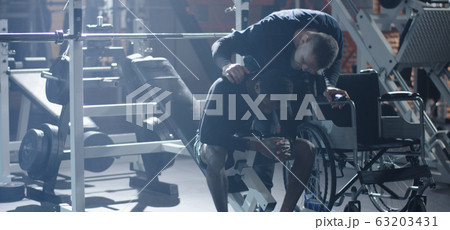 Wheelchair man lifting weight in gym Wheelchair man lifting weight in gym 63203431