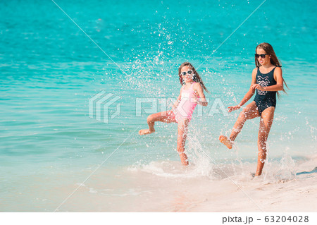 Little happy funny girls have a lot of fun at tropical beach playing together. 63204028
