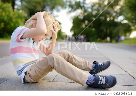 Little boy fell in the street, hit his head. 63204313