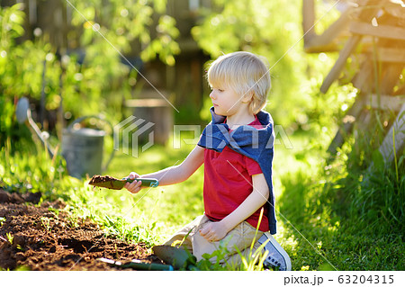 Little boy dig shoveling in backyard at summer Little boy dig shoveling in backyard at summer 63204315