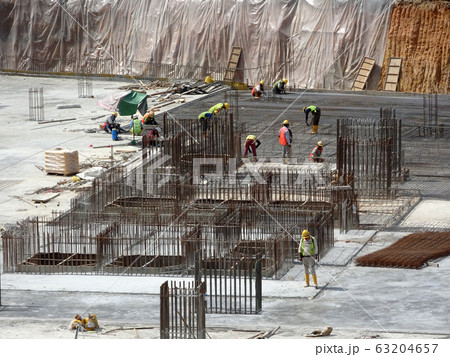 An aerial image of the construction site where the column is actively provided on the slab for the next level. Workers are working in stages. An aerial image of the construction site where the column is actively provided on the slab for the next level. Workers are working in stages. 63204657