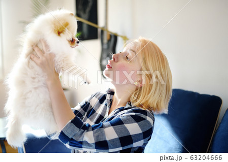 Young woman play with 2-month old pomeranian spitz 63204666