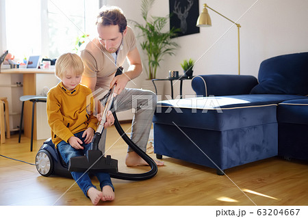Young handsome father teaches his son how to use a vacuum cleaner Young handsome father teaches his son how to use a vacuum cleaner 63204667