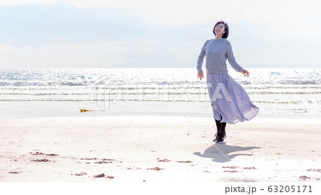 波打ち際 砂浜で遊ぶ健康なミドル女性  健康イメージ 63205171