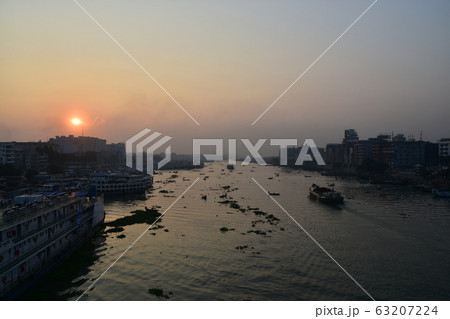 バングラデシュのダッカ　美しい朝日と古い街並み　ブリゴンガ川沿いに停留する客船　川を行き交うボート 63207224