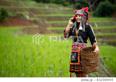 Portrait of Asia hmong lady calling by mobile phone while walking in rice field 63209444