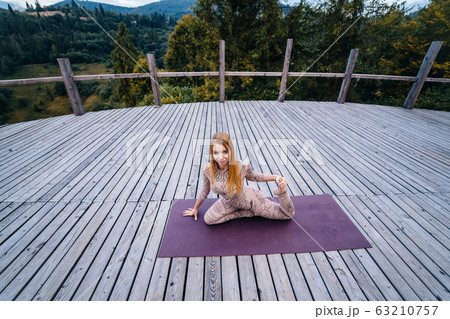 A woman practices yoga at the morning in a terrace on a fresh air. A woman practices yoga at the morning in a terrace on a fresh air. 63210757