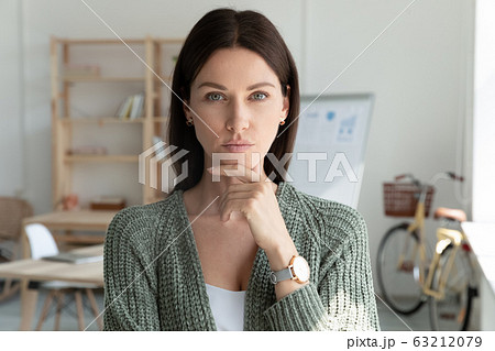 Thoughtful young female leader company owner looking at camera. Thoughtful young female leader company owner looking at camera. 63212079