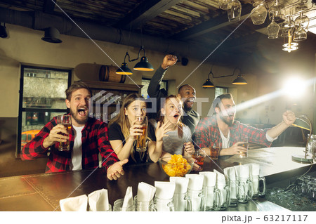 Sport fans cheering at bar, pub and drinking beer while championship, competition is going 63217117