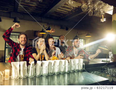 Sport fans cheering at bar, pub and drinking beer while championship, competition is going 63217119