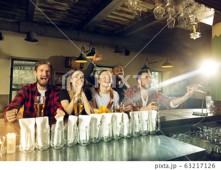 Sport fans cheering at bar, pub and drinking beer while championship, competition is going 63217126