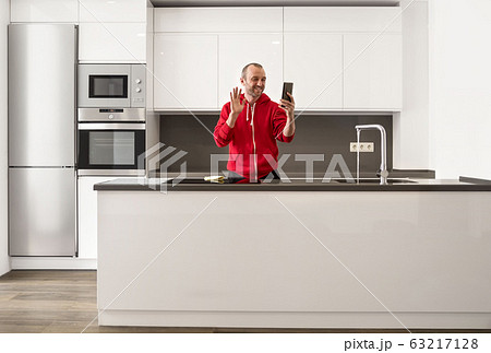 Happy man having fun and talking online video call in the kitchen at home 63217128