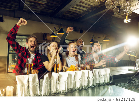 Sport fans cheering at bar, pub and drinking beer while championship, competition is going 63217129