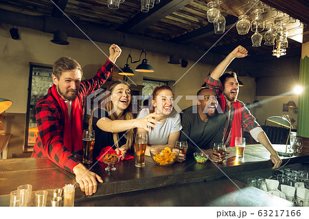 Sport fans cheering at bar, pub and drinking beer while championship, competition is going Sport fans cheering at bar, pub and drinking beer while championship, competition is going 63217166