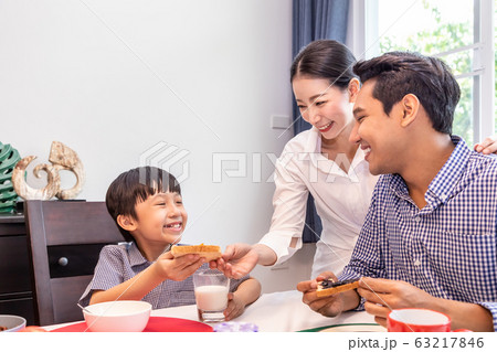 Happy Asian family in dining room, mother serving 63217846
