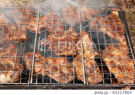 Juicy pork steak cooking on an open flame grill. 63217864