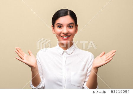 happily excited attractive woman in white shirt and red lips with hands up and open palms 63219094