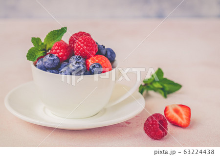 Fresh berries in a porcelain cup on pink concrete Fresh berries in a porcelain cup on pink concrete 63224438
