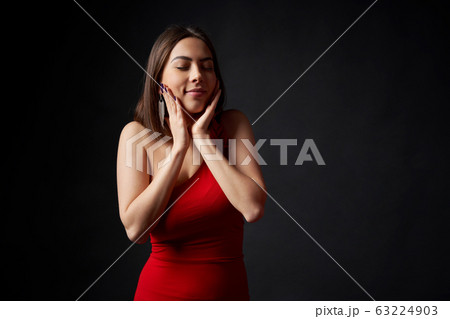 Surprised woman in red evening gown dreaming with closed eyes 63224903
