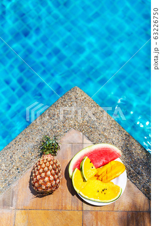 Juicy tropical fruits set at pool edge with 63226750